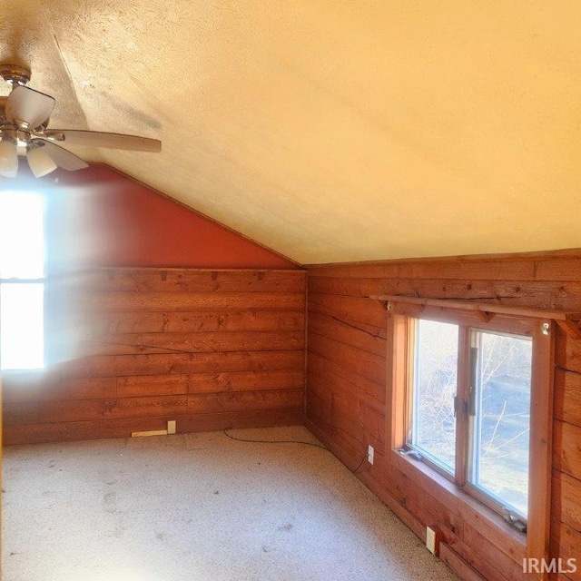 bonus room featuring light carpet, wooden walls, a textured ceiling, and lofted ceiling