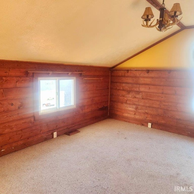 unfurnished room featuring rustic walls, visible vents, vaulted ceiling, and carpet flooring