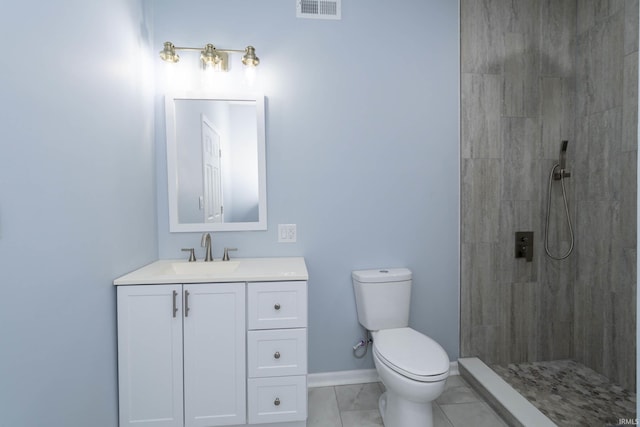 bathroom featuring toilet, visible vents, tiled shower, and vanity