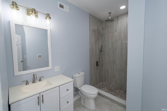 bathroom with visible vents, toilet, vanity, tile patterned flooring, and tiled shower