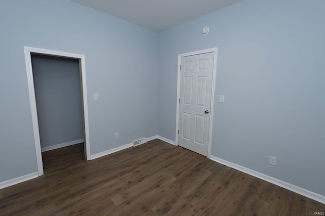 empty room featuring baseboards, visible vents, and dark wood-type flooring