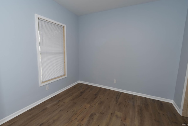 unfurnished room featuring dark wood-type flooring and baseboards