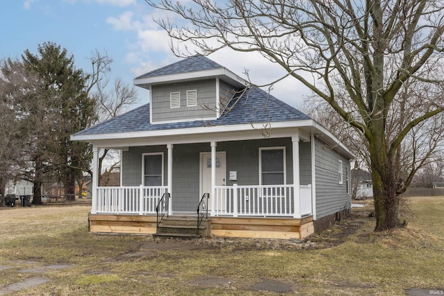 bungalow featuring covered porch, a shingled roof, and a front yard