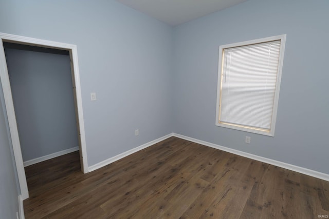 unfurnished bedroom with baseboards and dark wood-type flooring