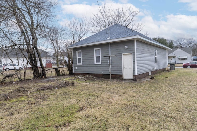 back of property featuring roof with shingles, a yard, and fence