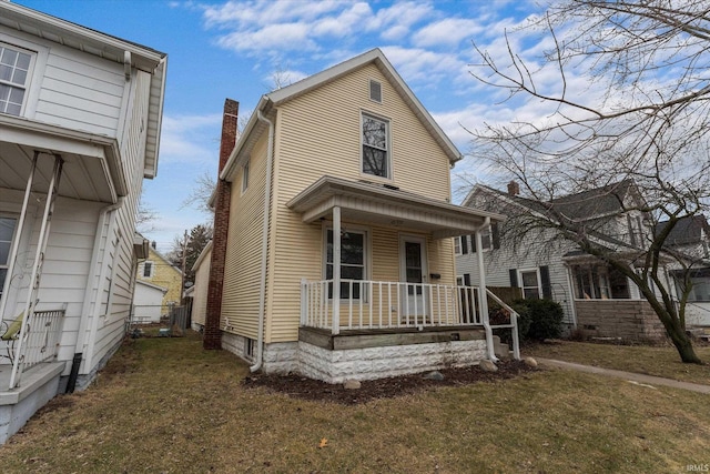 view of front facade featuring a chimney, a porch, and a front yard