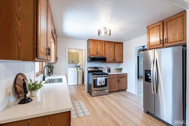 kitchen featuring light wood-style flooring, stainless steel appliances, a sink, light countertops, and brown cabinetry