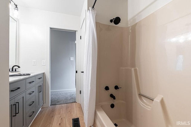 full bathroom with vanity, shower / bath combo with shower curtain, wood finished floors, and visible vents