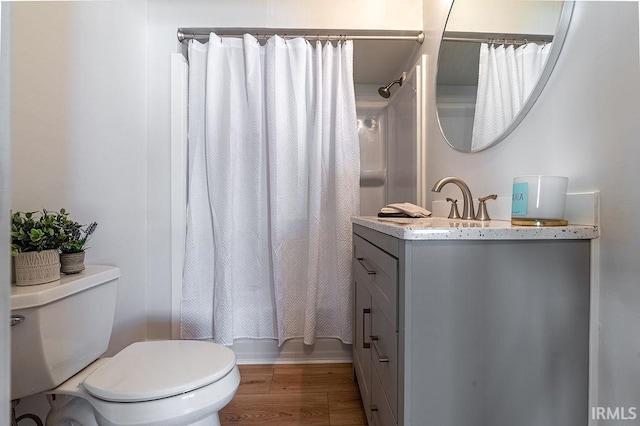 full bath with toilet, wood finished floors, and vanity