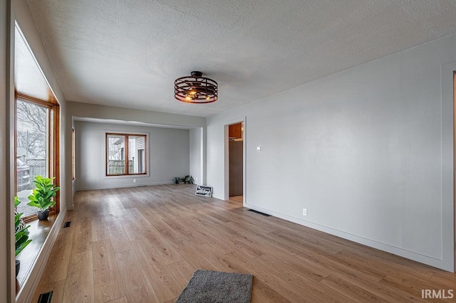 unfurnished room with visible vents, a textured ceiling, and light wood finished floors