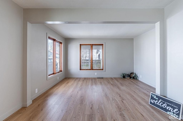 unfurnished room featuring visible vents, light wood-style flooring, and baseboards