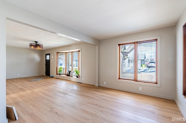 unfurnished room with light wood-type flooring, baseboards, and a wealth of natural light