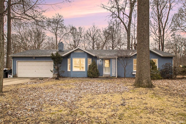 ranch-style home featuring a garage, driveway, and a chimney