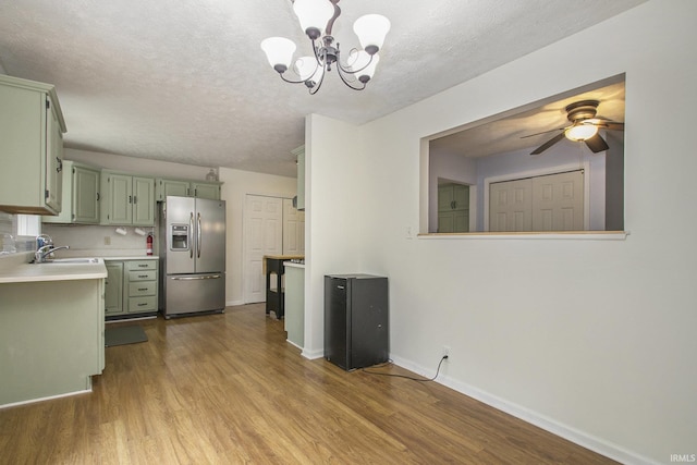 kitchen featuring green cabinetry, stainless steel fridge with ice dispenser, wood finished floors, light countertops, and a sink