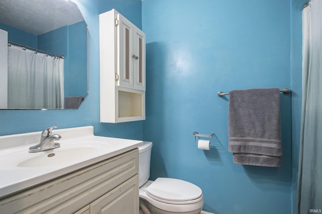 full bath featuring a textured ceiling, vanity, and toilet