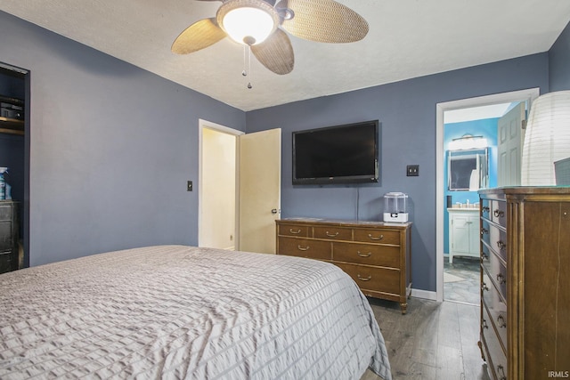 bedroom featuring baseboards, a ceiling fan, dark wood-style flooring, and ensuite bathroom