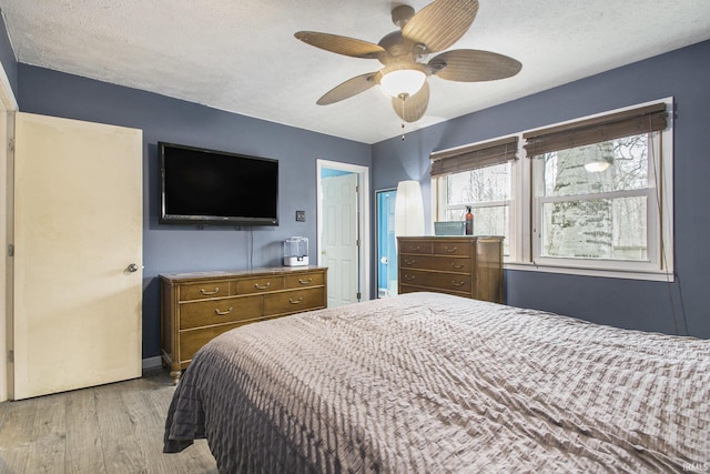 bedroom featuring a textured ceiling, light wood-type flooring, and a ceiling fan