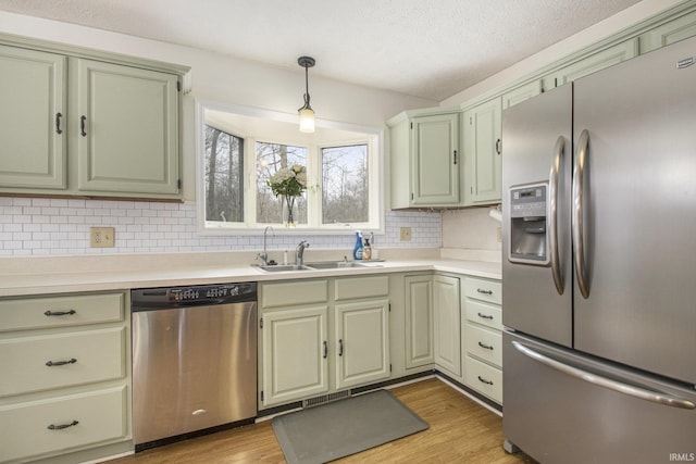 kitchen featuring light wood finished floors, appliances with stainless steel finishes, light countertops, and a sink