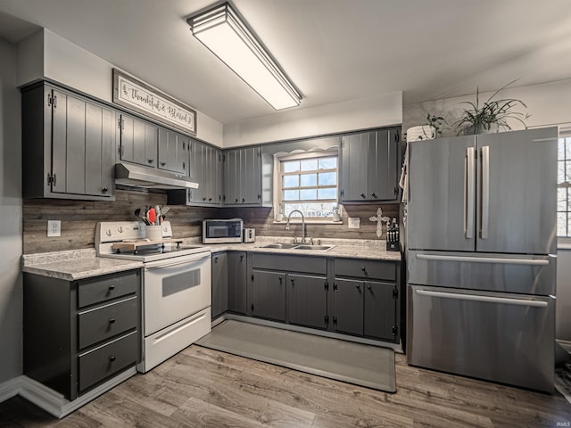 kitchen with gray cabinets, white electric range, under cabinet range hood, a sink, and freestanding refrigerator