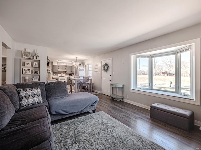 living room featuring baseboards, plenty of natural light, and dark wood-style flooring