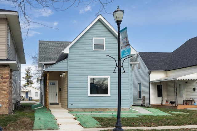 rear view of house featuring a shingled roof and a lawn