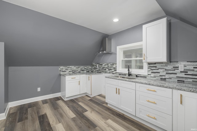 kitchen featuring light stone counters, dark wood-style floors, decorative backsplash, a sink, and baseboards