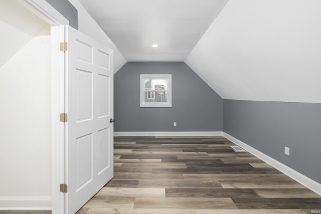 additional living space featuring lofted ceiling, wood finished floors, visible vents, and baseboards