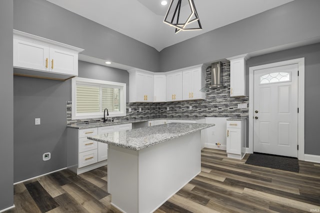 kitchen with wall chimney exhaust hood, dark wood-style flooring, light stone countertops, and white cabinets