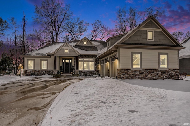 craftsman-style house with driveway, stone siding, and a garage