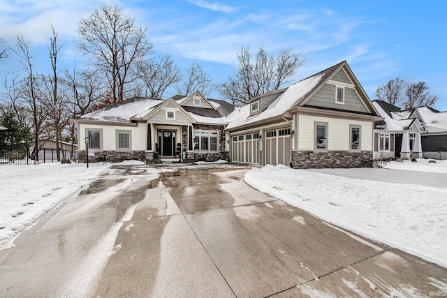 view of front of house with stone siding, concrete driveway, and fence