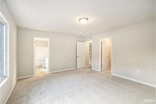 unfurnished bedroom featuring baseboards, a spacious closet, visible vents, and light colored carpet