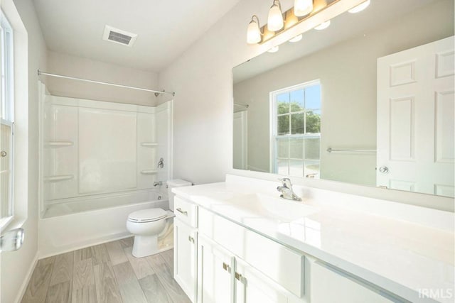 full bathroom featuring toilet, wood finished floors, vanity, visible vents, and shower / washtub combination