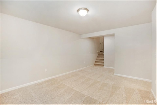 unfurnished room featuring light colored carpet, stairway, and baseboards