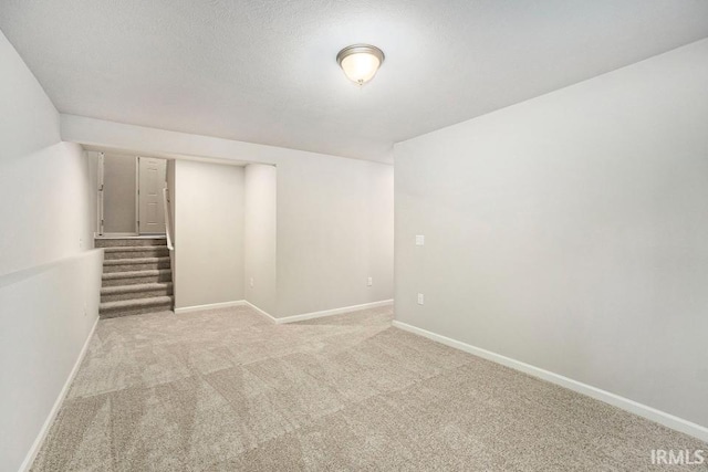 unfurnished room featuring carpet floors, baseboards, stairway, and a textured ceiling