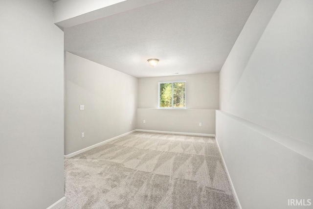 carpeted spare room featuring baseboards