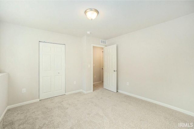 unfurnished bedroom with carpet floors, a closet, visible vents, and baseboards