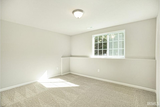 empty room featuring carpet floors, visible vents, and baseboards