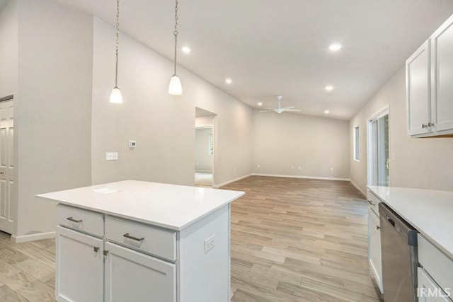 kitchen featuring vaulted ceiling, light countertops, stainless steel dishwasher, a center island, and light wood finished floors