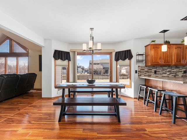 dining space featuring a notable chandelier, baseboards, and wood finished floors