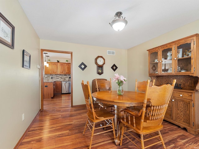 dining area with wood finished floors, visible vents, and baseboards