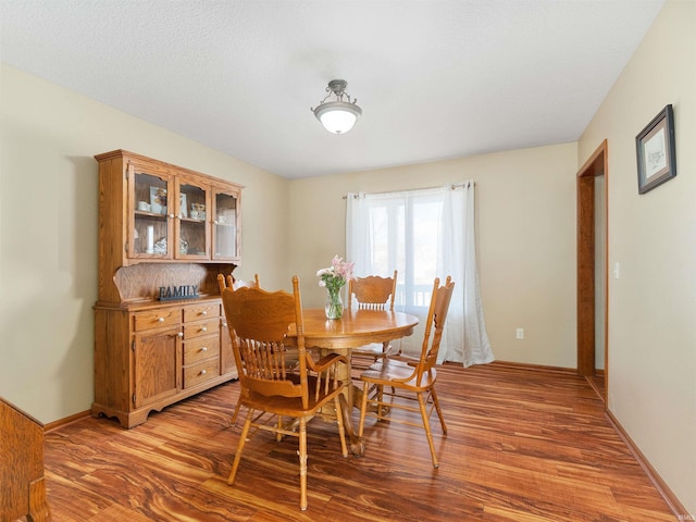 dining space with baseboards and wood finished floors