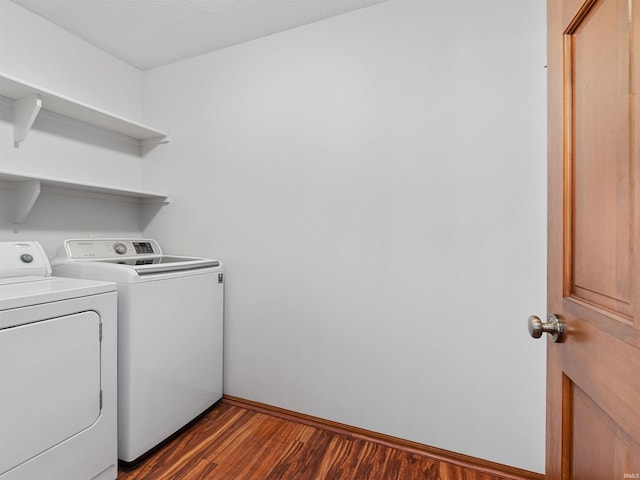 laundry area featuring dark wood-type flooring, washer and dryer, laundry area, and baseboards