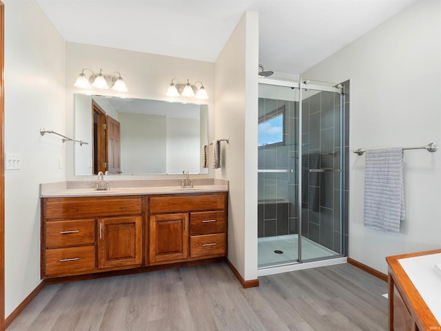 full bath featuring wood finished floors, a sink, a shower stall, and double vanity