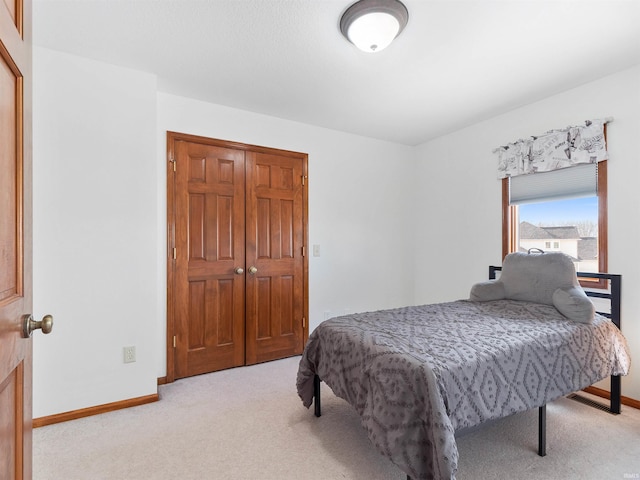 carpeted bedroom featuring a closet and baseboards