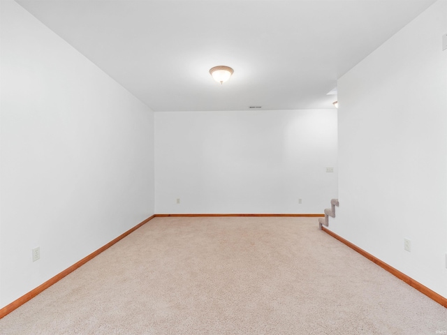 carpeted spare room featuring stairway, visible vents, and baseboards