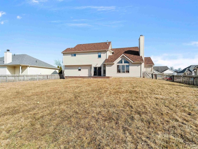 back of property featuring a yard, a chimney, and a fenced backyard