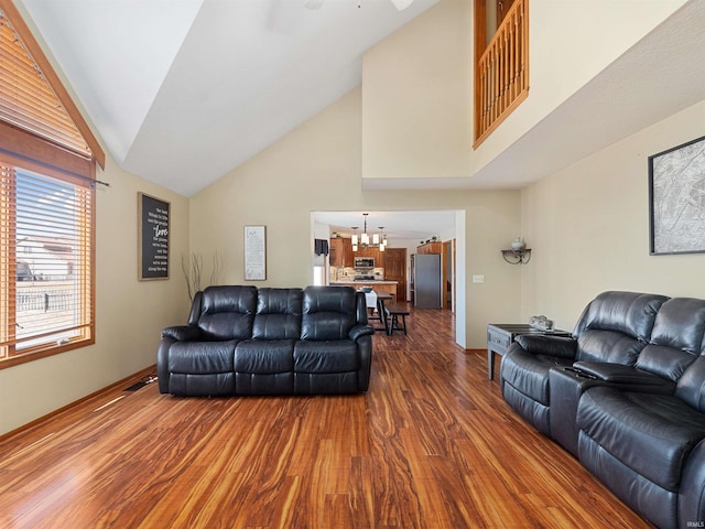 living room with a chandelier, high vaulted ceiling, visible vents, baseboards, and dark wood finished floors