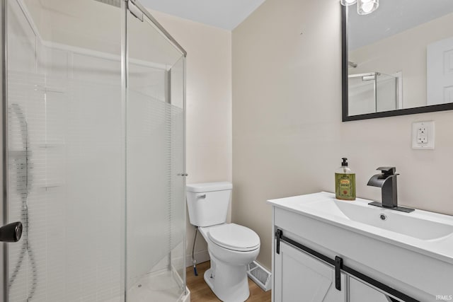 full bath with visible vents, toilet, a stall shower, vanity, and wood finished floors