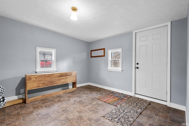 foyer featuring stone finish floor, a textured ceiling, and baseboards