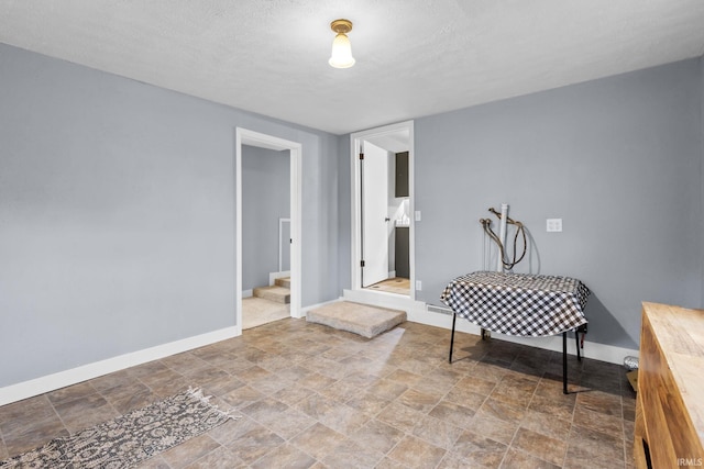 interior space with stairs, stone finish flooring, a textured ceiling, and baseboards